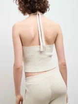 Top de punto acanalado color negro, con diseño de cuello halter y abertura frontal tipo gota.