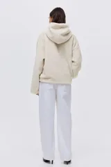 Campera de tejido suave con efecto de piel sintética, corte holgado y hombros caídos. Presenta capucha forrada, cierre frontal con cremallera y bolsillos laterales ocultos en las costuras.