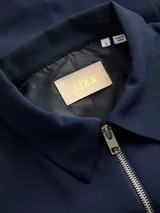 Chaleco ligero color azul marino con cuello camisero y cierre frontal de cremallera plateada. Diseño totalmente forrado y confeccionado en tejido plano.