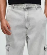 Pantalón de jean corte baggy con bolsillos cargo laterales, cierre de botón y cremallera, y cintura con trabillas.