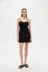 Short pollera negro de algodón y viscosa, de diseño holgado, con bordados decorativos y detalles metálicos en la cintura.