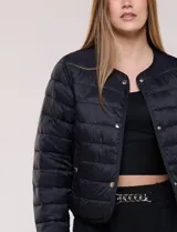 Campera puffer corta de diseño reversible y liviano, marca Michael Kors. Cuenta con acabado resistente al agua, diseño acolchado con matelaseado horizontal, cuello redondo a la base sin solapa ni capucha, cierre frontal completo con botones de presión metálicos, bolsillos laterales funcionales y ribetes a tono. Largo a la cintura y empacable en su propia bolsa de guardado.