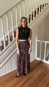 Falda larga de tiro alto, confeccionada en gasa de seda con estampado abstracto en tonos rosados y naranjas sobre base negra. Presenta diseño ajustado en la cadera con frunces y volado en el ruedo.