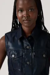 Chaleco azul marino de cuero sintético, con cuello camisero, cierre frontal con botones y bolsillos con solapa en el pecho.