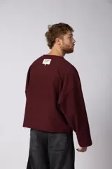 Buzo de cuello redondo confeccionado en tejido rústico, con diseño boxy, costuras a la vista y bordes al corte. Presenta estampas en el frente, la espalda y el interior, permitiendo un uso reversible.