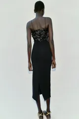 Vestido midi negro de punto con tirantes finos, escote recto adornado con aplicaciones de flores tridimensionales de tela satinada y abertura en la espalda.