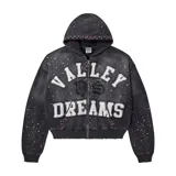 Campera tipo hoodie con cierre frontal, de color negro con efecto lavado. Presenta apliques de letras blancas con bordes deshilachados que forman la frase 'VALLEY DREAMS', decorada con múltiples strass brillantes y pequeñas piedras de colores en el borde de la capucha y bolsillos.