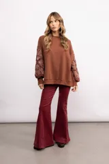 Buzo de algodón color negro con cuello redondo, mangas largas y bordado floral XL en color cobre en las mangas. Presenta un diseño holgado y cómodo.