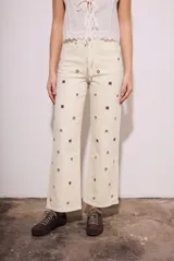 Jean de corte recto y tiro medio, color off-white, con diseño de pequeños bordados en forma de cruz distribuidos por toda la prenda.