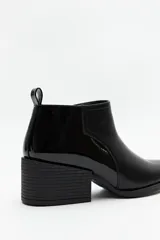 Botín negro de cuero sintético con punta fina, elástico lateral y taco ancho de 6cm.