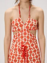 Top halter estampado en tonos rojo y beige, con tirantes finos ajustables al cuello y detalle de cuentas.