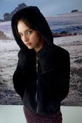 Chaqueta tipo teddy color negro, con capucha, cierre frontal metálico y puños tejidos.