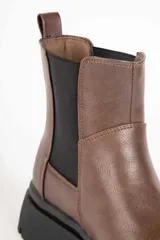 Bota Chelsea marrón de símil cuero con elásticos laterales negros y suela track negra.