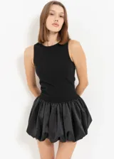 Vestido corto con cuerpo ajustado sin mangas y falda globo de satén con volumen.