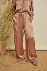 Pantalón de satén color tostado, de corte amplio y holgado, con pretina elástica de gasa deflecada y cordón ajustable, además de bolsillos laterales.