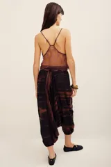 Pantalón babucha de algodón con estampa batik en tonos marrones y negros, tiro bajo y diseño amplio con puños elastizados en los tobillos.