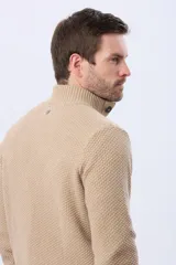 Buzo tejido texturado color verde oscuro, con cuello alto y cierre parcial de tres botones. Tiene mangas largas y un pequeño detalle de etiqueta marrón en el dobladillo inferior.