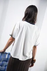 Remera de algodón color azul marino, corte relajado con hombro caído. Presenta cuello redondo blanco y bordado a mano en contraste en los puños de las mangas. Tiene un parche bordado en la parte inferior del frente.