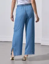 Pantalón celeste de lyocell, corte ancho, con pretina elastizada con lazo de ajuste, bolsillos verticales y ruedo desflecado.