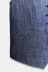 Chaleco sin mangas, color azul jaspeado, con escote pico y cierre frontal de cinco botones oscuros. Presenta falsos bolsillos de vivo en el delantero.