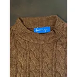 Buzo de punto blanco de manga larga con diseño trenzado y cuello redondo.