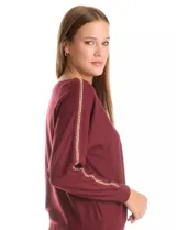 Buzo de tejido suave color bordó, con cuello a la base y mangas largas que presentan un aplique de cadena dorada a lo largo de la costura superior.