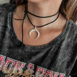 Gargantilla de cuero negro con dije de medialuna plateada.