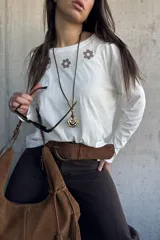Remera blanca de manga larga con detalles bordados de flores en marrón en la parte superior frontal.