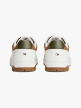 Zapatillas de corte bajo estilo retro baloncesto, confeccionadas en piel blanca con paneles de textura a contraste en color marrón y verde oliva en el talón. Presentan suela de goma dentada, cierre con cordones y logo de Tommy Hilfiger en el lateral y la lengüeta.