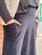 Pantalón tipo palazzo de tiro alto, confeccionado en plush de algodón con textura suave. Presenta un diseño amplio y fluido, con bolsillos laterales y una faja ancha en la cintura que brinda ajuste y comodidad.