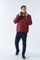 Campera puffer color bordó, con cuello alto y cierre frontal. Tiene bolsillos laterales con cierre y logo estampado en el pecho.