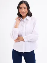 Camisa blanca de manga larga con cuello camisero, cierre frontal con botones y detalles de tablas verticales en el frente.
