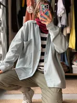 Sobrecamisa de jean color celeste claro, de corte oversize, con mangas largas, bolsillos frontales con solapa y cierre de botones.