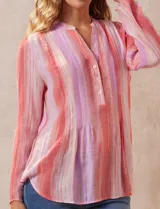 Blusa de gasa estampada con flores en tonos rosa, amarillo y azul. Tiene cuello a la base, escote en V y botones. La delantera tiene detalle plisado y las mangas son 3/4 regulables con presilla y botón.