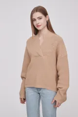 Sweater de tejido de punto en color beige, con cuello en V cruzado y mangas largas con puños ajustados.