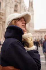 Guantes sin dedos confeccionados en cuero negro con ribetes de corderito al tono en los extremos. Presentan un diseño abrigado y una pequeña etiqueta de marca en el lateral.