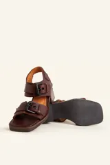 Sandalias de cuero negro con taco bloque de madera tallada, tiras con hebillas grandes y punta cuadrada.