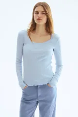 Remera celeste de manga larga en punto pointelle acanalado, con escote en U y detalles de ondas en los puños y el bajo.