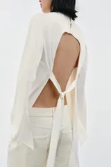 Top de viscosa con acabado satinado, cuello redondo y mangas largas acampanadas. Presenta un diseño de bajo asimétrico y cierre posterior con botones.