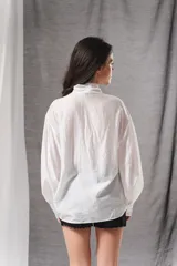 Blusa blanca holgada con mangas abullonadas y lazo en el cuello para anudar.