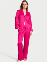 Pijama largo de satén jacquard fucsia con patrón de monograma, compuesto por una camisa de manga larga con botones y un pantalón con cintura elástica y cordón ajustable.