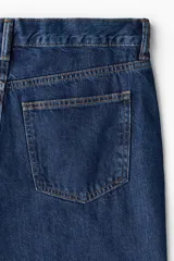 Pantalón jean de corte relajado en denim de algodón rígido, con diseño clásico de cinco bolsillos, cierre frontal de botón y cremallera, y piernas rectas.