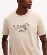 Remera de algodón color beige con cuello redondo, mangas cortas y estampa frontal con lettering y motivos botánicos.