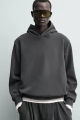 Sudadera tipo hoodie de corte relajado, confeccionada en tejido fluido con efecto lavado. Presenta cuello con capucha, mangas largas y terminaciones en rib.