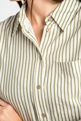 Camisa de corte oversize con estampado de rayas verticales, cuello clásico, cierre frontal con botones y bolsillo en el pecho. Presenta mangas largas con puños abotonados y un diseño fluido.