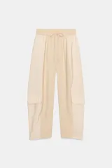 Pantalón de tiro medio con cintura elástica ajustable con cordón. Presenta un diseño de paneles laterales en tejido técnico contrastante y bolsillos tipo cargo. Su corte es holgado con pernera que se estrecha hacia el tobillo.