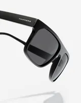 Gafas de sol unisex Hawkers modelo Cheedo, con montura cuadrada de color negro y lentes oscuros.