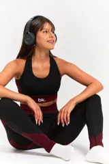 Conjunto deportivo de tres piezas compuesto por un top, una calza chupín de tiro alto y una campera corta con cierre frontal. El diseño presenta una combinación de texturas en color negro y detalles en bordó.