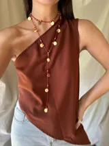 Collar largo rojo con cuentas doradas y dijes circulares dorados.