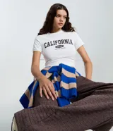 Remera de algodón blanca ajustada al cuerpo, con cuello redondo y manga corta. Cuenta con estampa frontal con el texto "CALIFORNIA EST.87 UNITED STATES".